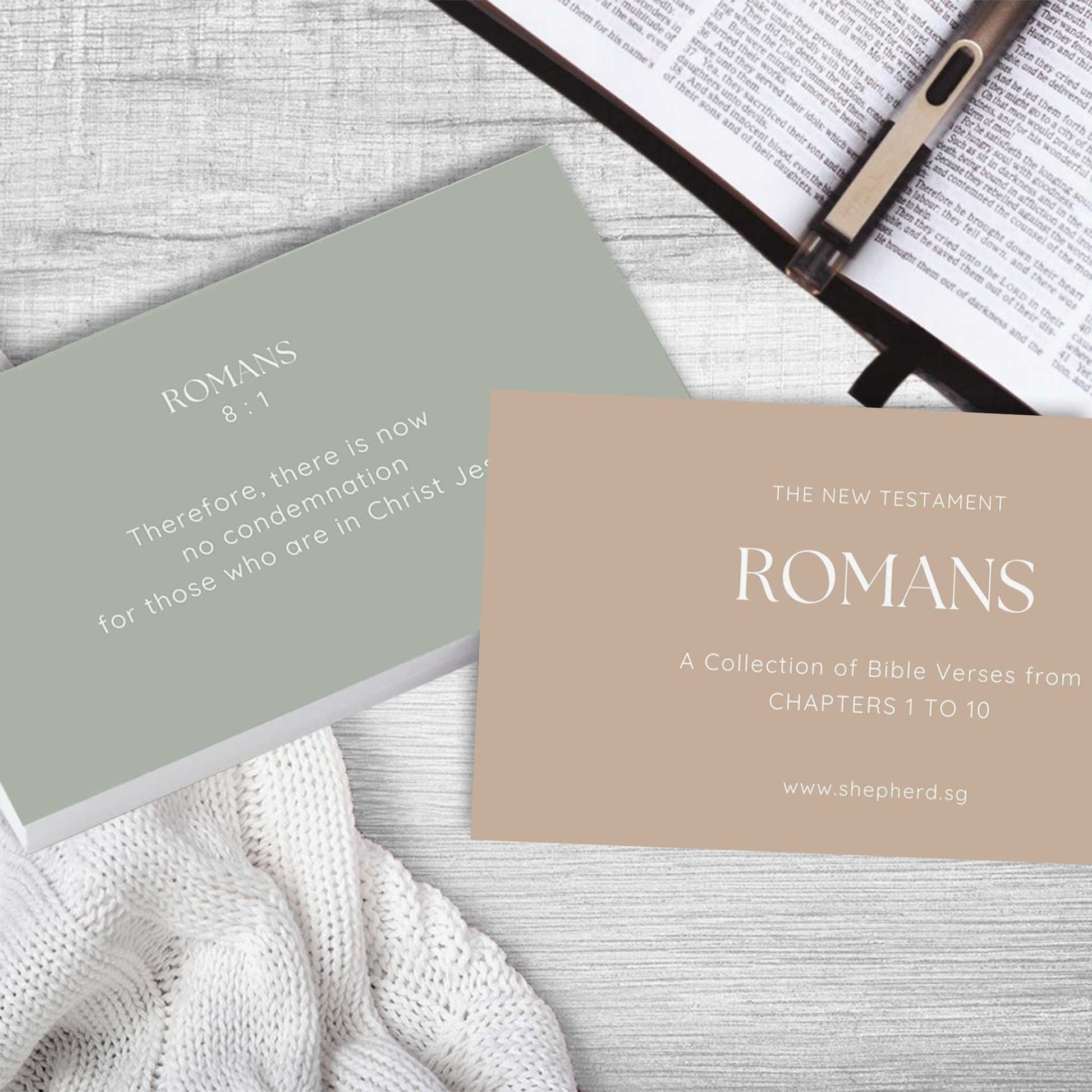 two cards with bible verse Romans on a bible and wooden top