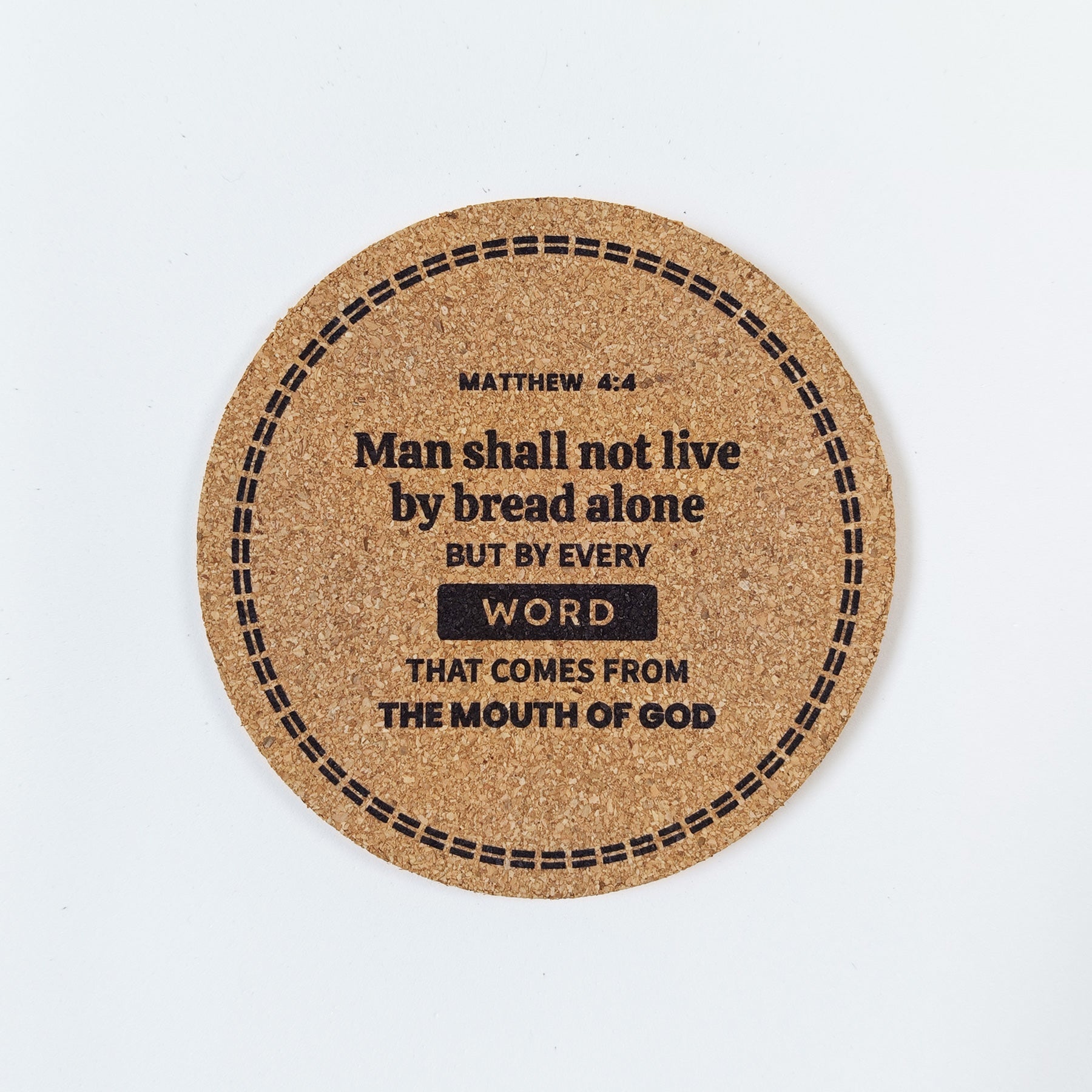 Circle cork coaster with Bible verse Matthew 4:4 Man shall not live by bread alone on a white background