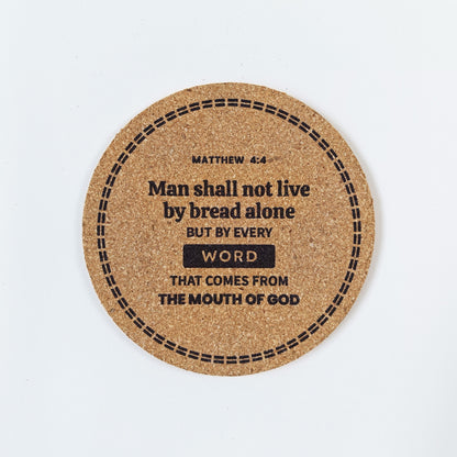 Circle cork coaster with Bible verse Matthew 4:4 Man shall not live by bread alone on a white background