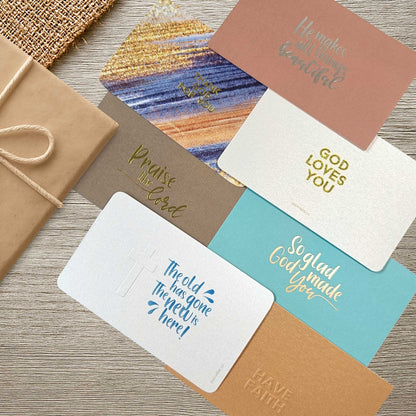 Set of Christian gift cards with gold and silver foil text on a wooden table top designed by shepherd.sg
