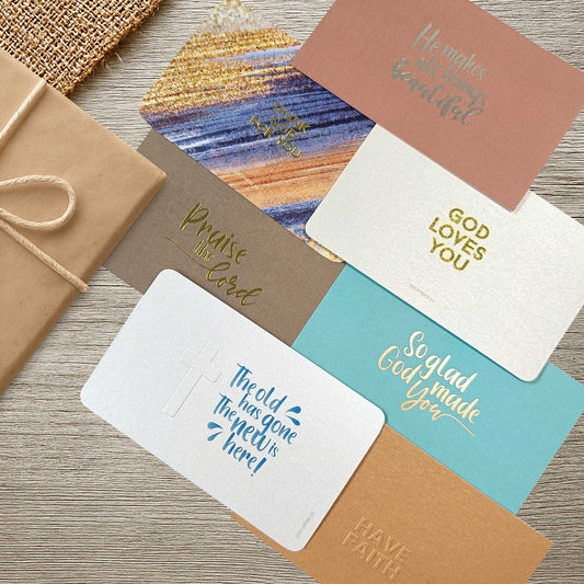 Set of Christian gift cards with gold and silver foil text on a wooden table top designed by shepherd.sg
