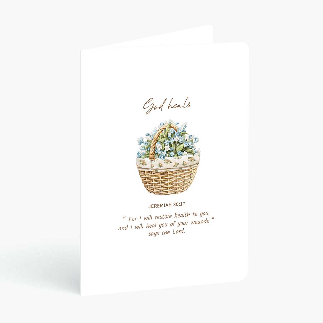 Christian greeting card God heals with bible verse from Jeremiah 30 and wicker basket of flowers on a white background