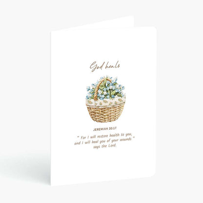 Christian greeting card God heals with bible verse from Jeremiah 30 and wicker basket of flowers on a white background