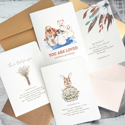 Collection of Christian greeting cards with various designs and bible verses on a rustic wooden top