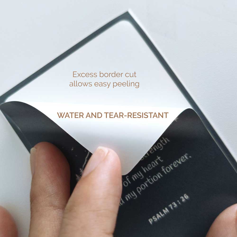 Water and tear-resistant sticker designed by Shepherd.SG being hand peeled on a grey background