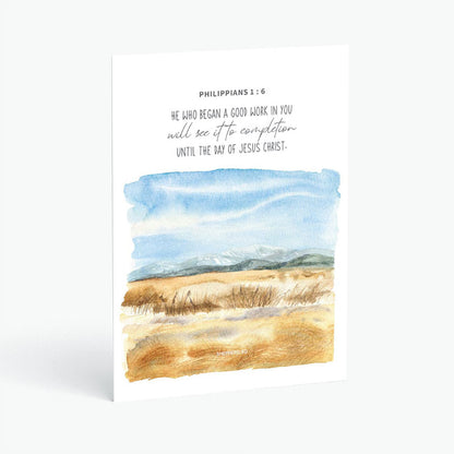 Christian postcard with Bible verse Philippians 1:6 and watercolor design of mountains in the horizon, blue skies and brown fields on white background